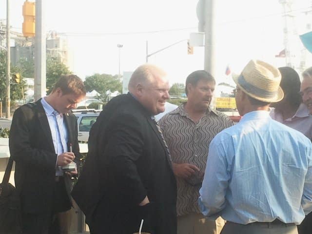 6 people gathered talking to each other, city intersection in the background, outside